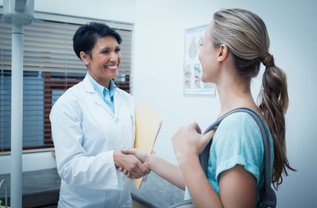 A woman in an dentist's office shaking hands with her dentist