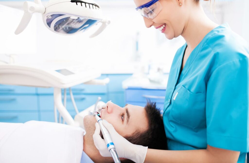 A dentist cleaning the teeth of her patient.