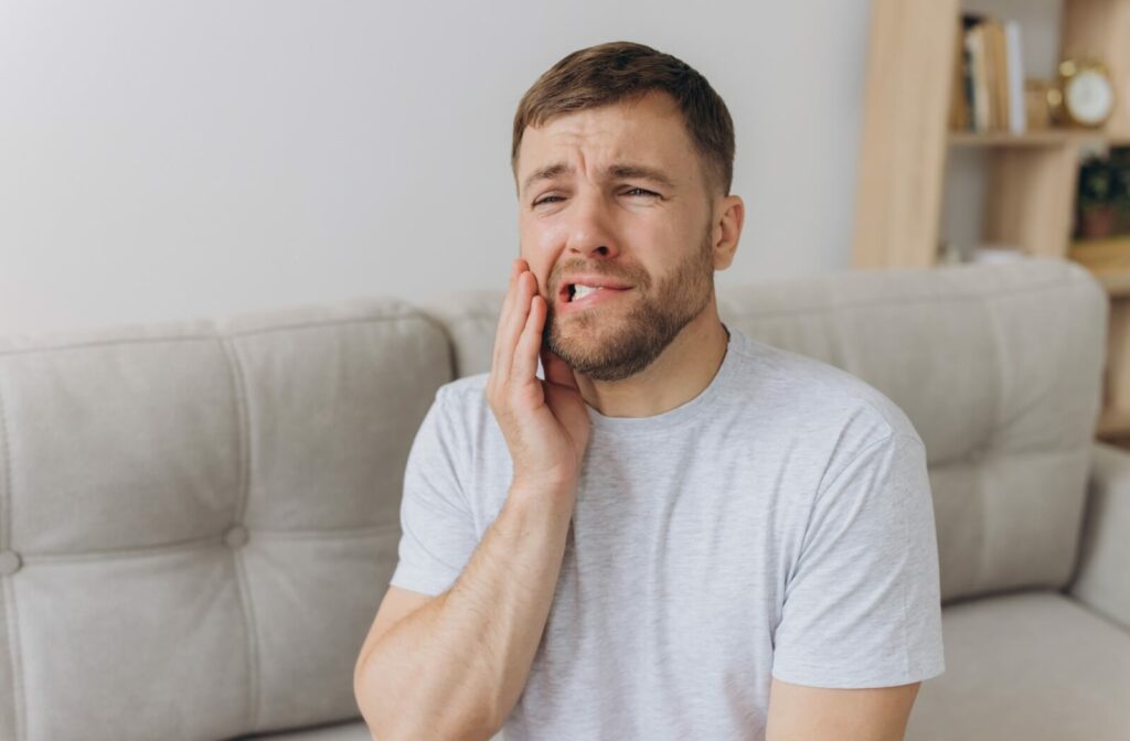 An adult massages the side of their face, suspecting they may have a TMJ disorder causing the discomfort.