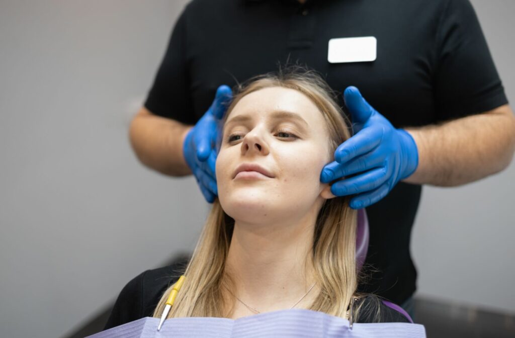 A dentist performs an external examination of their patients jaw to determine whether TMJ is causing their symptoms.