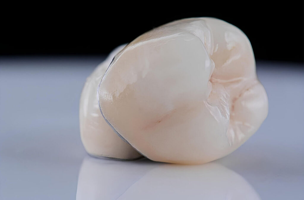 Close-up of a dental crown on a reflective surface against a black backdrop.