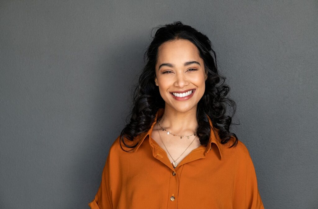 A person, happy with their dental implants, smiles for a photo, showing off their new, healthy smile.