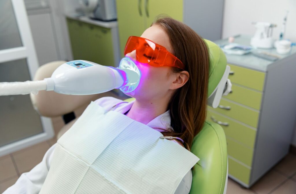 Someone relaxes in the dental office during their teeth whitening appointment. They recline comfortably in the seat as they wait.
