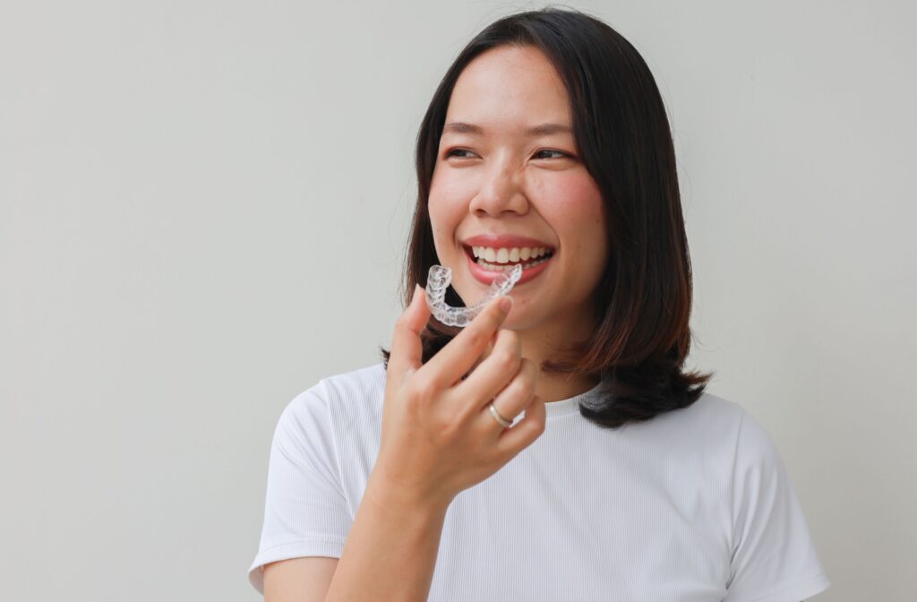 A person holding an invisalign tray and smiling