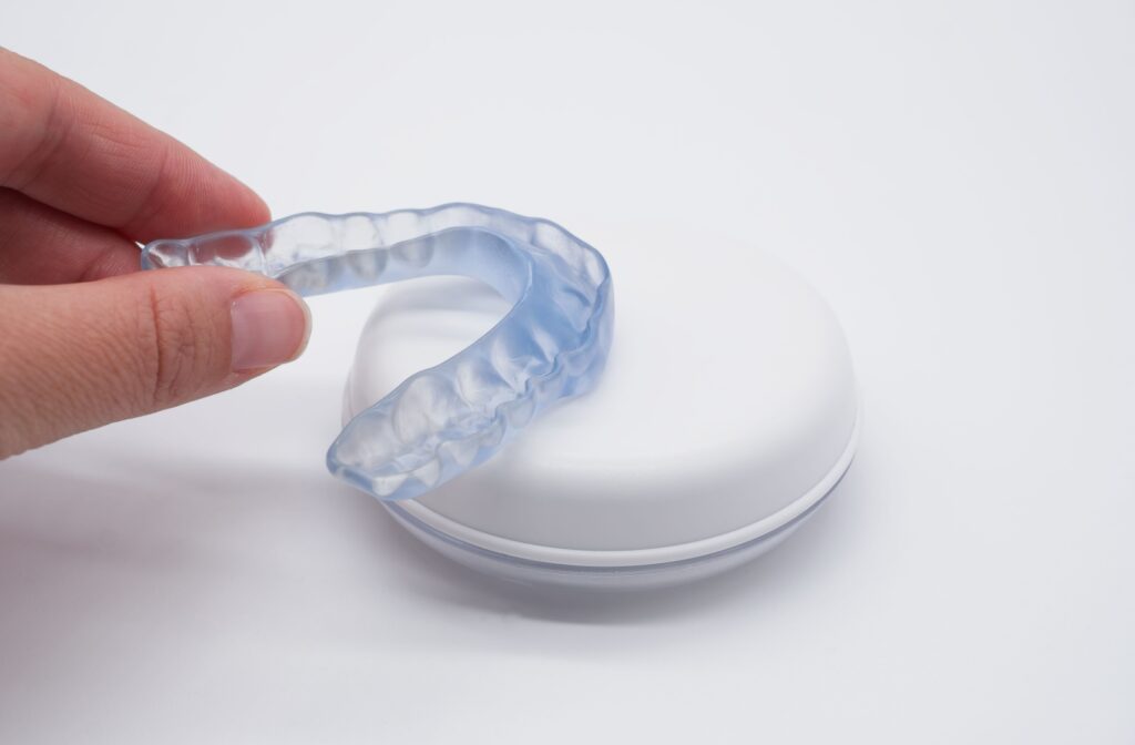 A clear dental nightguard hovering over a retainer case