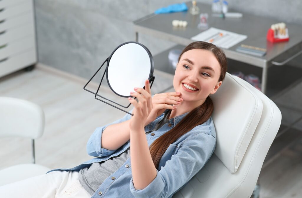 A person looking at their teeth in the mirror at the dentist